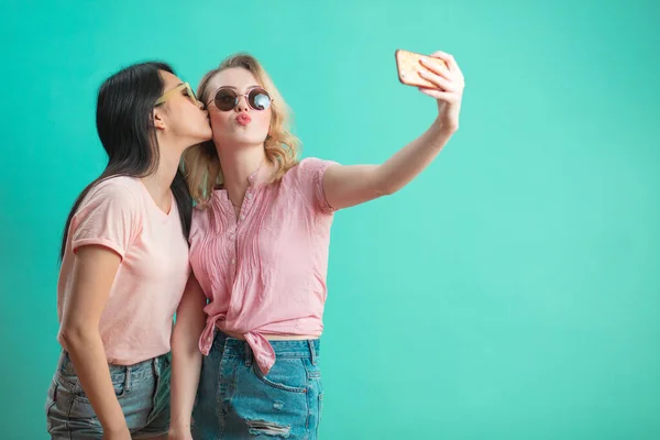 Diversas chicas en trajes casuales disparando selfie aislado sobre fondo azul. — Foto de Stock