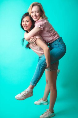 İki eğlenceli ırklar arası kız stüdyoda eğleniyor ve sırtına biniyor.