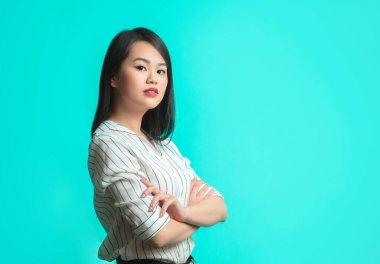 Mavi arka planda izole edilmiş genç Asyalı kadın portresi