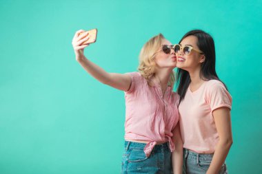 Farklı kızlar günlük kıyafetlerle çekim yapıyor. Mavi arka planda izole edilmiş selfie çekiyorlar..