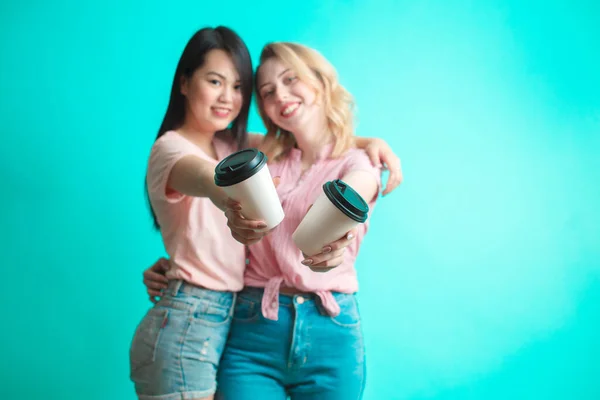 Casal de meninas multirraciais segurando takeaway café isolado sobre azul — Fotografia de Stock