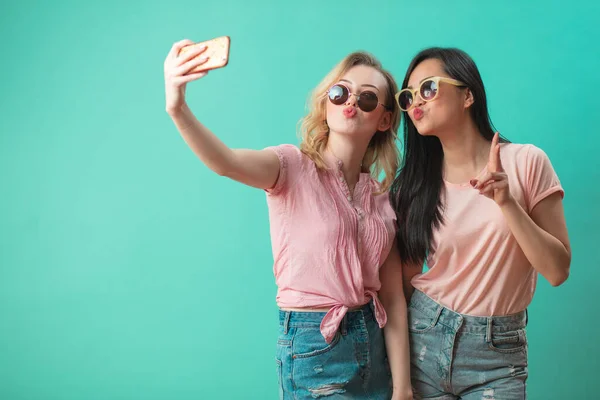 Felice diverse giovani ragazze prendendo selfie con smartphone contro muro blu — Foto Stock