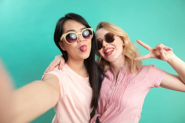 Porträtt av två glada kvinnor vin solglasögon isolerade på blått — Stockfoto