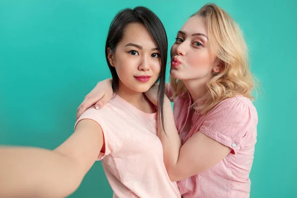 Diverse Mädchen in lässigen Outfits schießen Selfie isoliert auf blauem Hintergrund. — Stockfoto