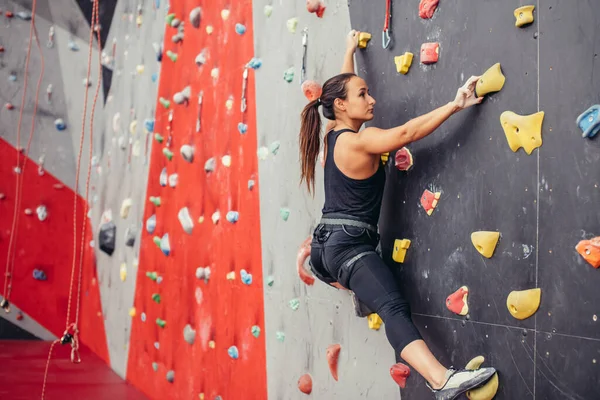 Young climber woman climbing on practical rock in climbing center, bouldering — Stock Photo, Image
