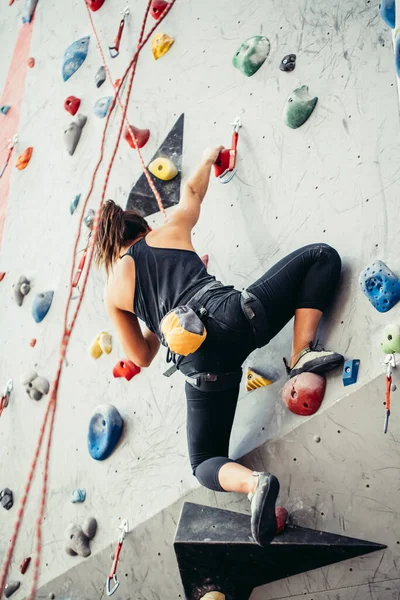 Mujer joven deportiva entrenando en un colorido gimnasio de escalada. Chica escaladora libre subiendo a interior —  Fotos de Stock