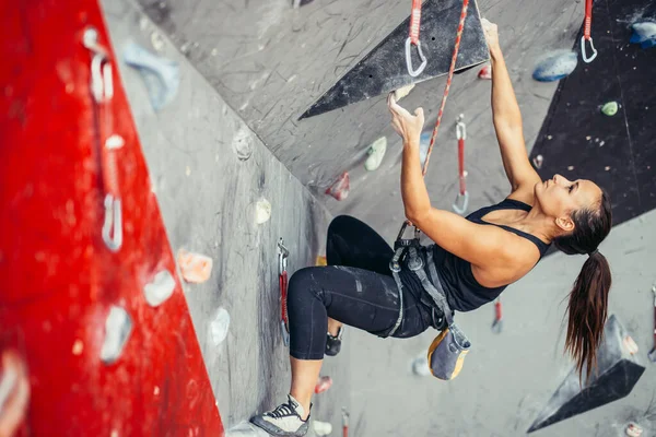 Sportowa młoda kobieta trenująca na barwnej sali wspinaczkowej. Bezpłatny wspinaczka dziewczyna wspinaczka się wewnątrz — Zdjęcie stockowe