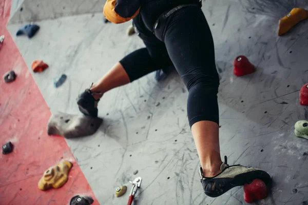 Close up of athletic woman practicing rock climbing on artificial wall indoors. — Stock Photo, Image