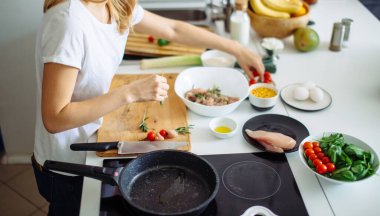 Kadın mutfakta et ve sebzeden kebap yapıyor.