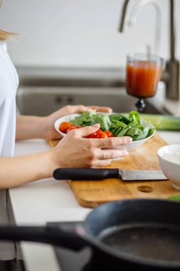 Kadın taze sebzelerden sağlıklı salata yapıyor.