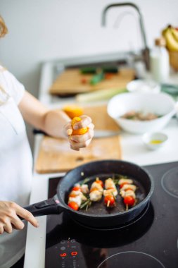 Genç ve mutlu ev kadınının akşam yemeği için tavuk eti kızartışı görüntüsü.