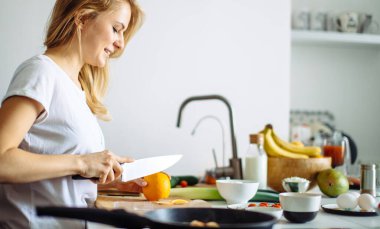 Genç bayan aşçı mutfakta yemek pişiriyor.