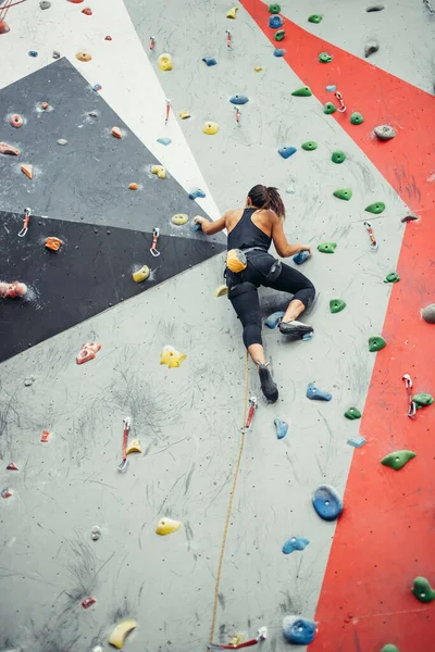 Schöne junge Frau macht einen großen Schritt auf einer künstlichen Mauer — Stockfoto