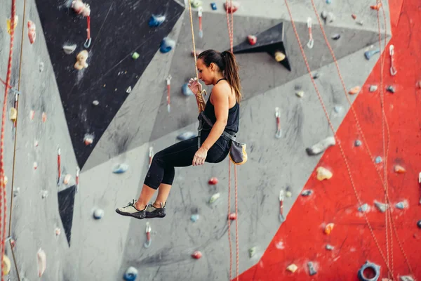 Beautiful young woman taking a big step up an artificial wall — Stock Photo, Image