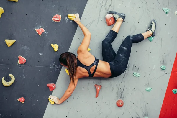 Beautiful young woman taking a big step up an artificial wall — Stock Photo, Image