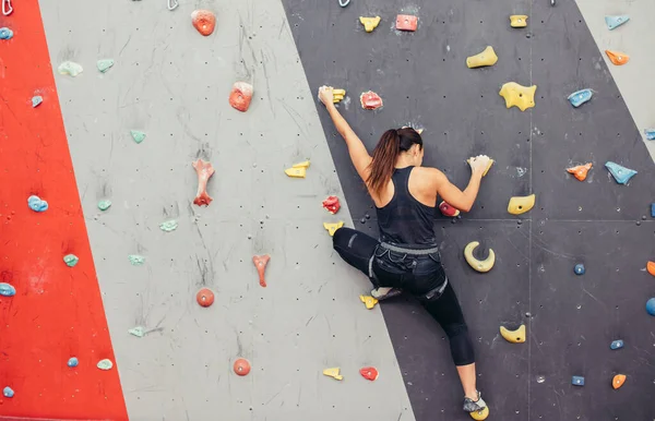 Jovem alpinista subindo na rocha prática no centro de escalada, pedregulho — Fotografia de Stock