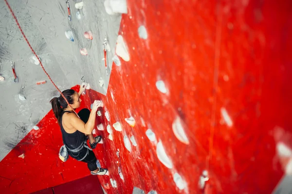 Vista de alto ângulo da mulher praticando escalada em uma placa do campus. Mulher escalando em uma placa do campus em um ginásio de escalada na parede. — Fotografia de Stock