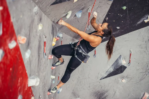 Νεαρή γυναίκα κάνει επαγγελματική bouldering στην αναρρίχηση γυμναστήριο σε εσωτερικούς χώρους — Φωτογραφία Αρχείου
