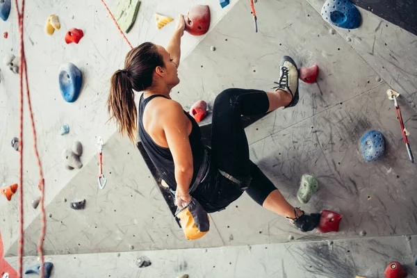 Renkli bir tırmanma salonunda spor yapan genç bir kadın. Serbest dağcı kız içeri tırmanıyor. — Stok fotoğraf