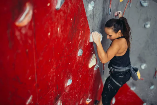 Güzel, genç ve güçlü bir kadın kırmızı duvar üst manzarasına tırmanıyor.. — Stok fotoğraf