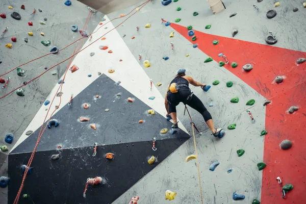 Beautiful young woman taking a big step up an artificial wall — Stock Photo, Image