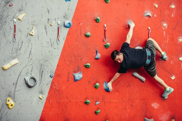 Hombre en el muro de escalada de ejercicio artificial —  Fotos de Stock