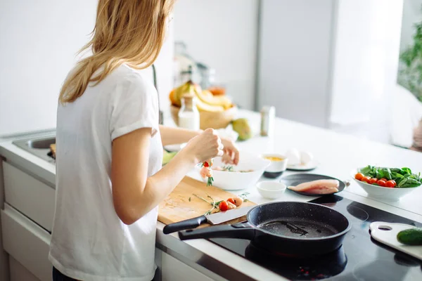 Ung hemmafru lagar mat till sänglinne i köket. Bakifrån — Stockfoto