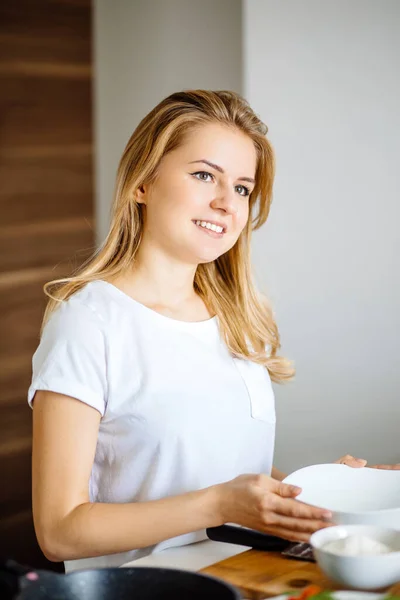 Atractiva mujer rubia posando en la mesa en su cocina — Foto de Stock