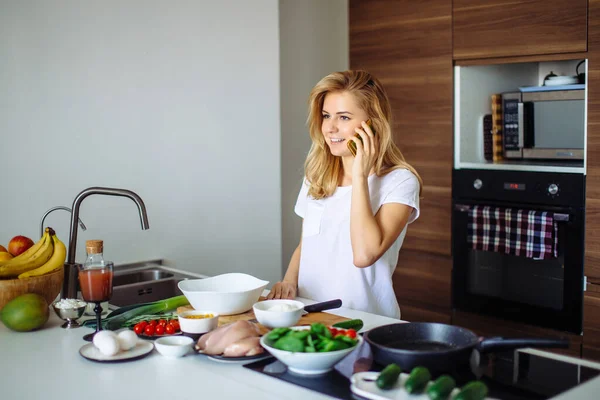 Kaukasische Frau macht gesunde Mahlzeit und liest Nachricht am Telefon in der Küche. — Stockfoto