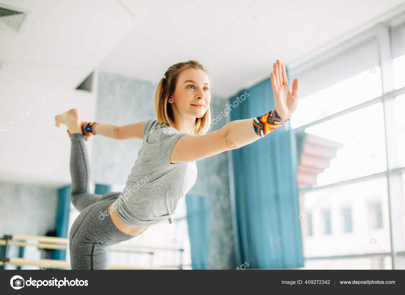 Young fit woman doing a yoga pose standing with one leg raised up. Stock  Photo by ©ufabizphoto 409272342