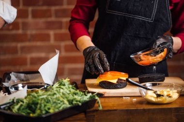 Şef sığır eti, salata ve sebzeli bir burger hazırlar..