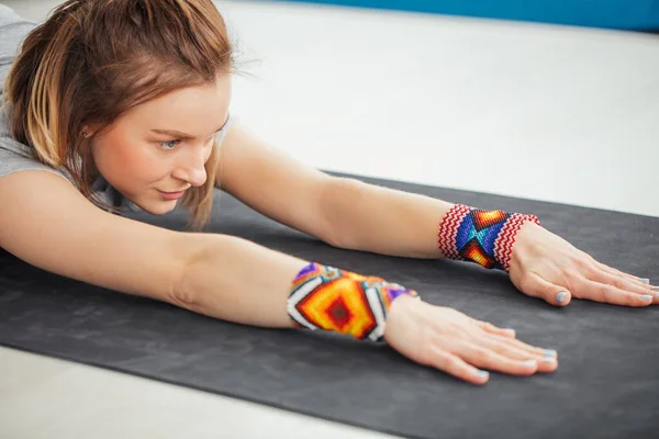 Fitness woman stretching her hands exercising yoga in hall — Stock Photo, Image