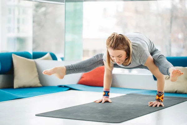 Yoga woman doing balance handstand pose exercises at gym