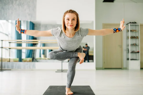 Mujer haciendo ejercicios de equilibrio durante un entrenamiento de yoga en un gimnasio bien iluminado — Foto de Stock