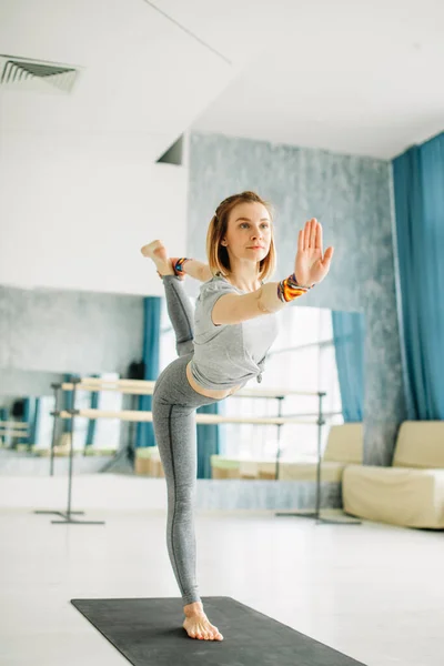 Joven mujer en forma haciendo una pose de yoga de pie con una pierna levantada. — Foto de Stock