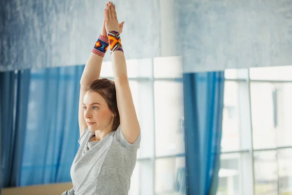 Fitness mujer estirando sus manos ejercitando yoga en la sala — Foto de Stock