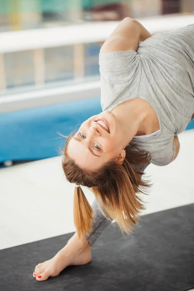 Женщина практикует йогу, треугольная поза в фитнес-центре — стоковое фото