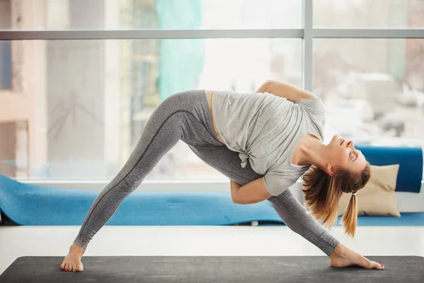 Mujer practicando yoga, pose triangular en gimnasio — Foto de Stock