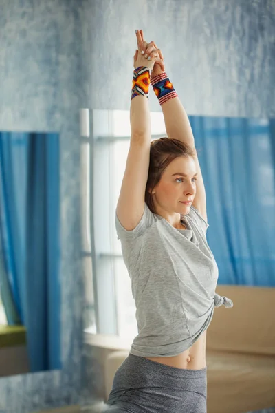 Фитнес-женщина, протягивая руки, занимаясь йогой в холле — стоковое фото