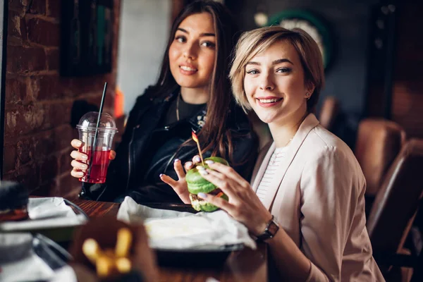 Две подруги ужинают с зеленым сэндвичем в бургер-баре. — стоковое фото