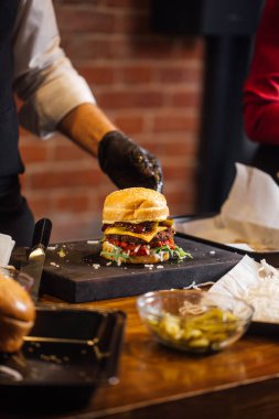 Bir grup genç, hamburgercide leziz hamburgerlerini yiyorlar.