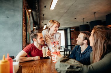 Mutlu arkadaşlar içecekler içerken kafede birlikte vakit geçirirken eğleniyorlar.