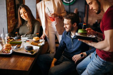 Lokantadaki müşterilere hamburger getiren kibar genç garson.