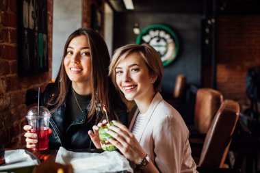 İki kız arkadaş hamburgercide yeşil sandviçle yemek yiyorlar..