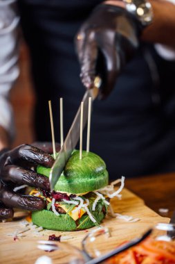 Şef sığır eti, salata ve sebzeli bir burger hazırlar..