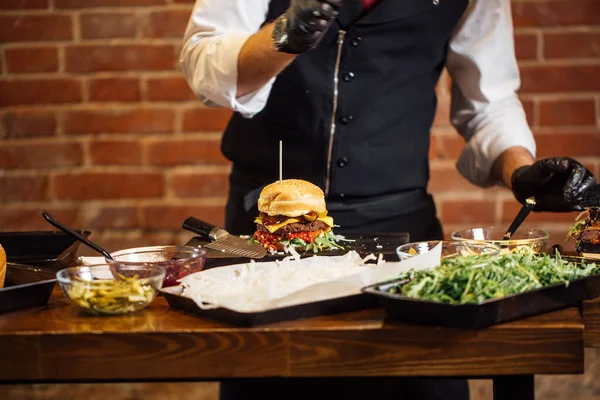 Szef kuchni przygotowuje hamburgera z wołowiny, sałatki i warzyw. — Zdjęcie stockowe