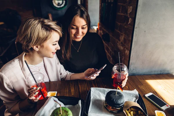 Donna d'affari mangiare un delizioso hamburger nel ristorante utilizzando smartphone — Foto Stock