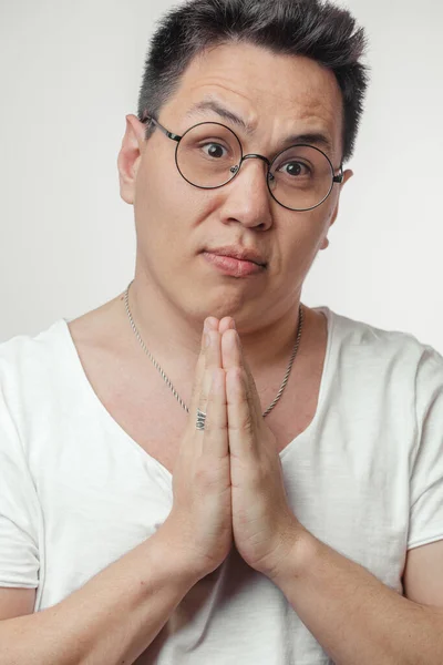 Asian man in t-shirt, holding hands in pray, begging for help or asking apology — Stock Photo, Image