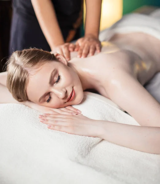 Young woman taking pleasure on massage bed, with eyes closed. Woman. Spa salon. — Stock Photo, Image