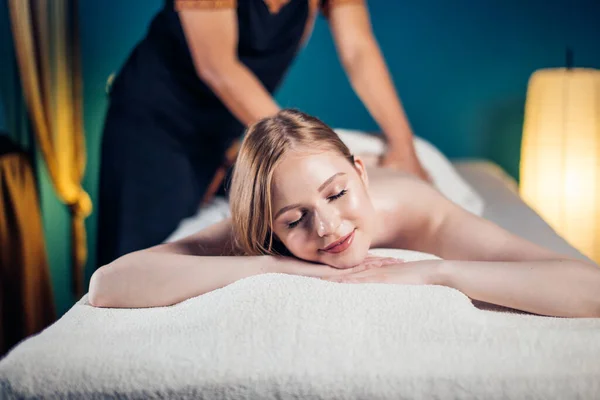 Giovane donna che prende piacere sul lettino da massaggio, con gli occhi chiusi. Una donna. Salone termale. — Foto Stock